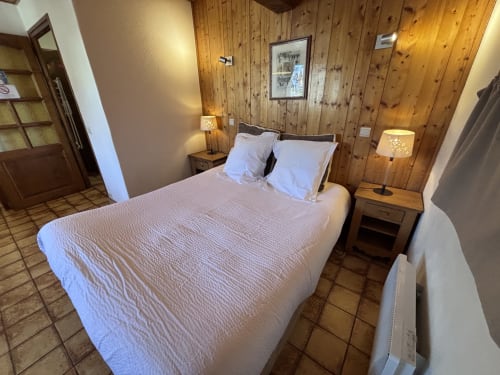 Cozy bedroom at Chez Francine in Notre Dame de Bellecombe with wooden walls, double bed, nightstands, and warm lighting