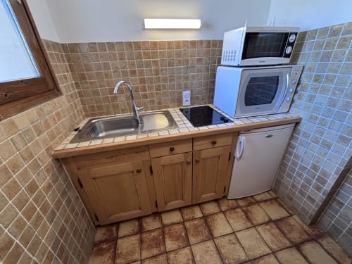 Studio Aravis kitchenette with wooden cabinets, sink, stove, and microwave at Chez Francine