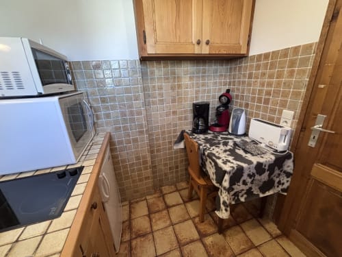 Compact kitchen area in Studio Aravis at Chez Francine with tile backsplash, wooden cabinets, and appliances
