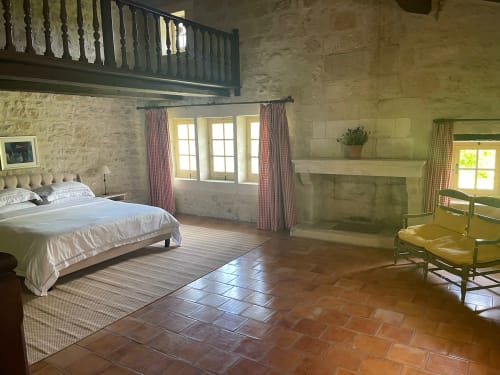 Chambre spacieuse en Provence avec murs en pierre apparente, mezzanine, cheminée et vue sur le jardin à Conciergerie Maurin