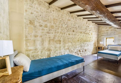 Chambre spacieuse à la Conciergerie Maurin à Arles avec murs en pierre, poutres apparentes, lits jumeaux et décor rustique