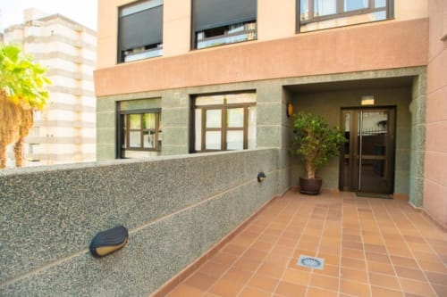 Moderner Apartmenteingang in Santa Cruz de Tenerife mit Terrakottahof, Steinmauern und dunklen Holztüren