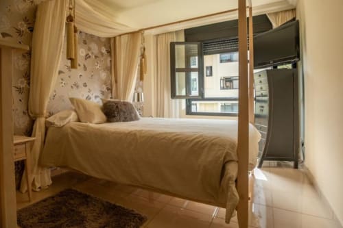Elegantes Schlafzimmer mit Himmelbett, cremefarbener Bettwäsche und Blumentapete in der Residencial Anaga, Santa Cruz de