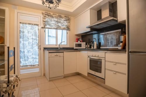 Moderne Küche in der Residencial Anaga Wohnung, Santa Cruz de Tenerife, mit cremefarbenen Schränken und Edelstahlgeräten