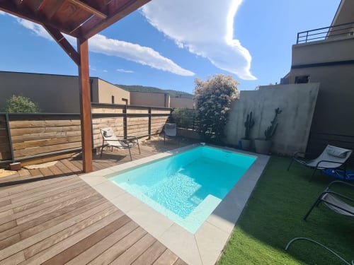 Villa Corsica pool with turquoise water, wooden deck, lounge chairs, and mountain views managed by Corsu Di Core, Favone