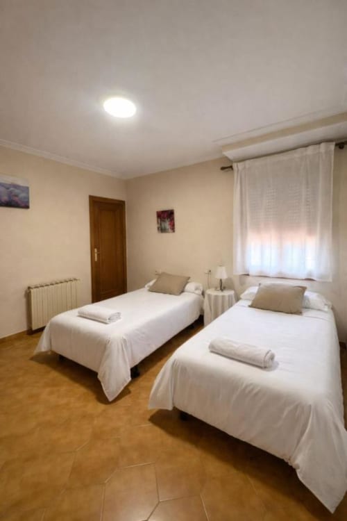 Dormitorio doble con sábanas blancas en Casa Rural Finca El Olivar, Valencia - hotel rústico con suelo de madera y ventana