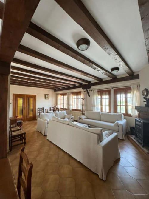 Amplio salón rústico en Casa Rural Finca El Olivar con vigas de madera vista, sofás color crema y muebles de época