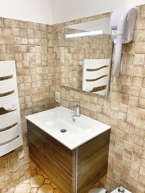 Studio Lachat bathroom at Chez Francine with beige tile walls, white sink vanity, and mirror in Notre Dame de Bellecombe
