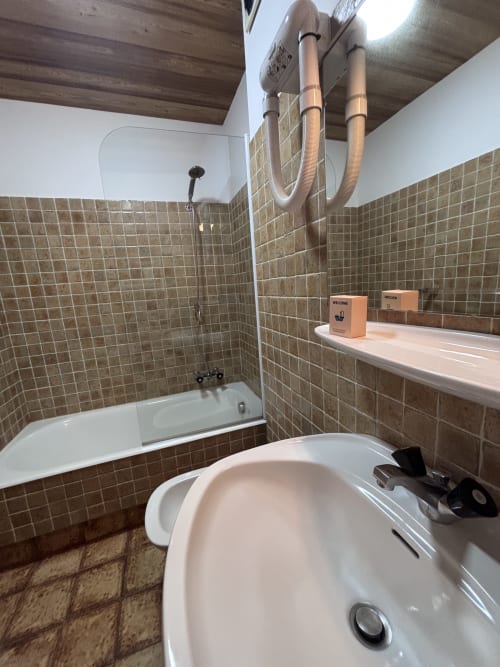 Modern bathroom in Studio Ban rouge at Chez Francine with tiled walls, bathtub, sink, and pedestal basin in Notre Dame de