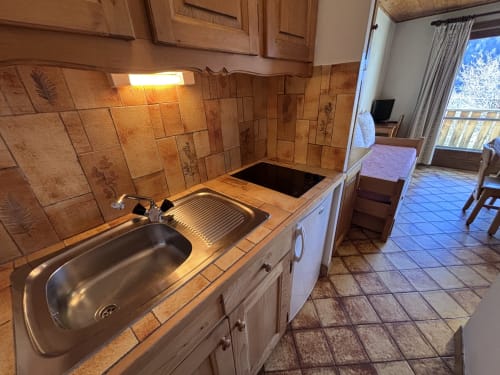 Studio kitchen at Chez Francine with tile backsplash, stove, sink and access to living area