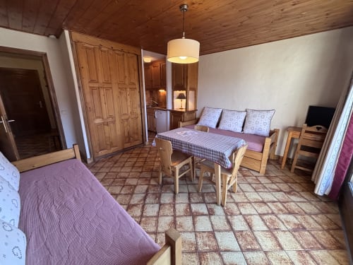 Studio apartment at Chez Francine with wooden ceiling, purple bedding, dining area, and TV in Notre Dame de Bellecombe