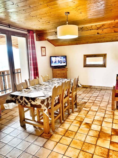 Spacious dining area in Chez Francine apartment with wooden beams, TV, and mountain views in Notre Dame de Bellecombe.