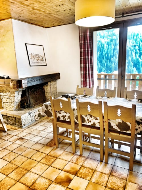Alpine dining room at Chez Francine with wood chairs, fireplace, and mountain forest views through French doors