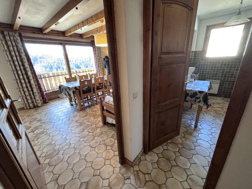 Open-plan dining and kitchen area in Appartement Mont Rond with mountain views, wooden beams, and hexagonal tile flooring