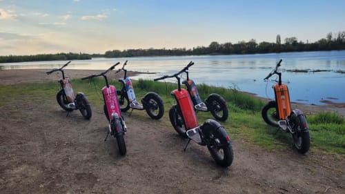 Colorful electric scooters lined up on sandy beach overlooking calm water at Les Gîtes d'Amélie in Morton