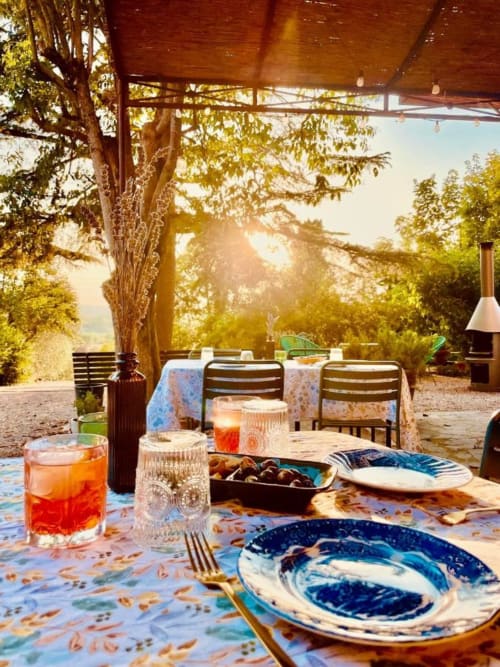 Sunset dining at Agriturismo CasaViva in Tuscany with colorful plates, golden light through trees