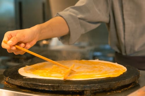 Un chef prépare des crêpes à La Maison 1903, un gîte en Trévou-Tréguignec, France