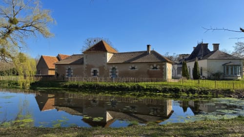 Cloffy B&B in Nouans-les-Fontaines with lake view, featuring historic stone buildings reflected in calm water