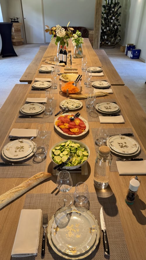 Mise en place élégante à la salle de réception Cloffy avec table en bois massif, couverts, légumes frais, bouteilles de vin et