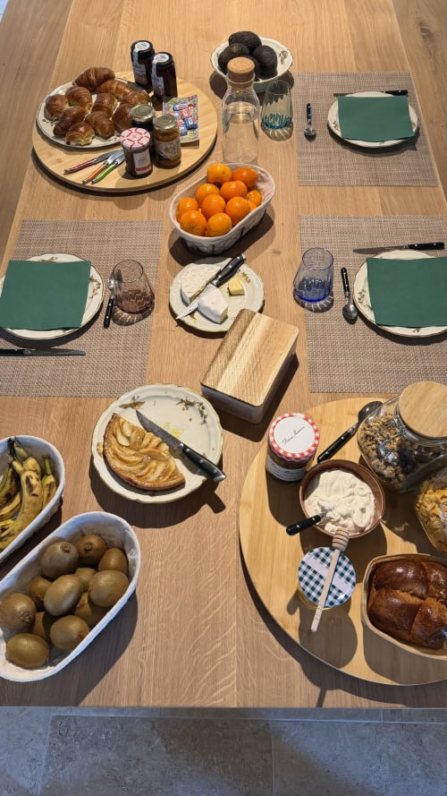 Table du petit-déjeuner à Cloffy B&B à Nouans-les-Fontaines avec viennoiseries, fruits frais, fromage et pain sur table en bois