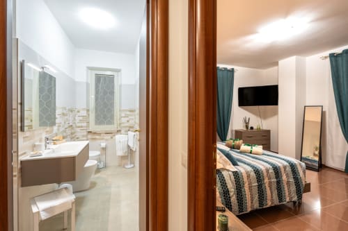 Camera Grecale Deluxe at Torre dei Venti, Ceccano: bedroom with striped bedding and modern bathroom with shower and vanity