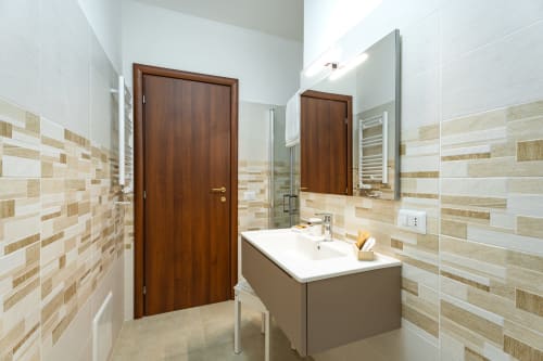 Modern bathroom at Torre dei Venti B&B in Ceccano with wood-grain tiles, floating sink, mirrors, and wooden doors