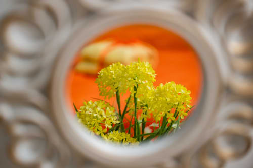 Fiori gialli incorniciati da una finestra in pietra decorativa alla Torre dei Venti, Ceccano, con tramonto arancione sullo sfondo