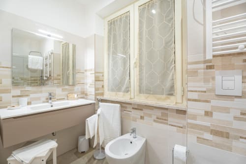 Bagno moderno nella Torre dei Venti B&B di Ceccano con piastrelle a righe, lavabo, bidet e doccia con tenda decorata