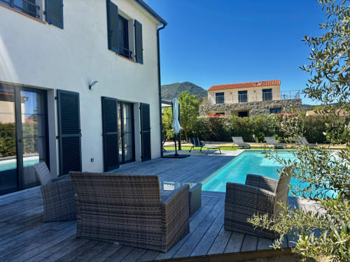 Modern villa patio with private pool, wicker seating, and mountain views in Zilia