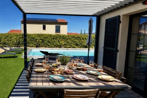 Outdoor dining setup at Belle villa Amanduli with set table, private pool, and mountain views in Zilia, France