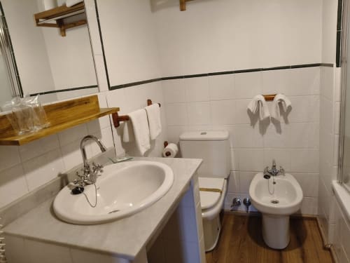 Modern bathroom at Posada La Colodra with round sink, toilet, bidet, and tiled walls