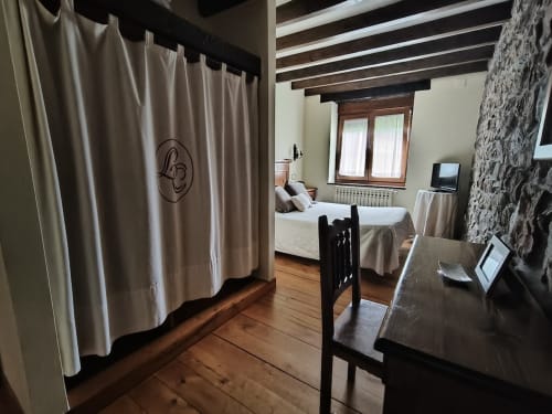 Posada La Colodra double room with wooden beams, desk, beds, and mountain view windows