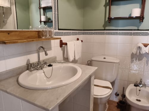 Bathroom at Posada La Colodra with white sink, toilet, bidet and tiled walls