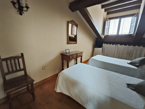 Twin bed bedroom at Posada La Colodra with mountain view, wooden beams, desk, and rustic Spanish décor