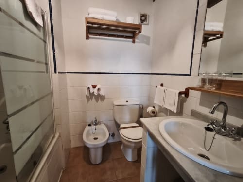 Bathroom with double sink, toilet, bidet, and shower in Posada La Colodra hotel room