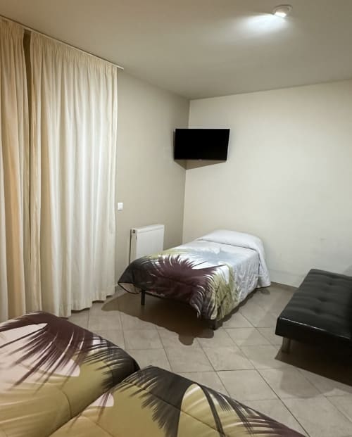 Studio bedroom at Apartamentos Turisticos Raquel's with twin beds, flat-screen TV, cream curtains and tiled flooring