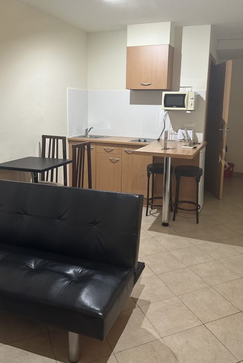 Studio apartment kitchenette with dining area and black leather sofa at Apartamentos Turisticos Raquel's in Sant Pere