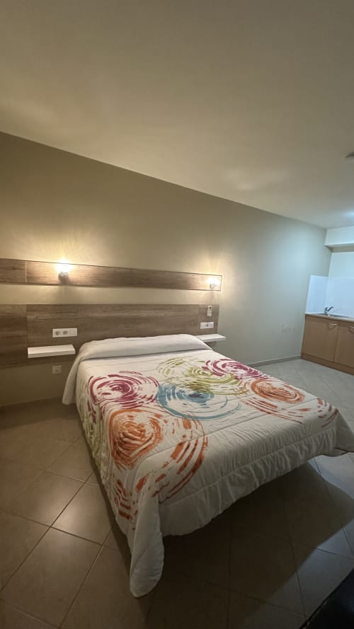 Modern double bedroom at Apartamentos Raquel's, Sant Pere Pescador, with wooden headboard, accent lighting, and colorful