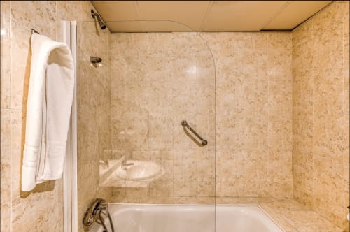 Modern bathroom shower with marble tiling and glass door at Raquel's hotel, Sant Pere Pescador