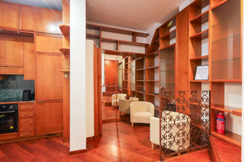 Monolocale moderno a Milano con mobili in legno di ciliegio, cucina a vista e arredi contemporanei presso l'hotel Solumnia