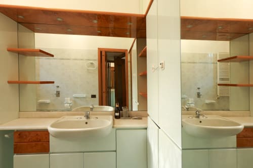 Bagno moderno dello studio The Urban Nest a Milano con doppi lavandini, docce in vetro, scaffalature in legno e arredi contemporanei