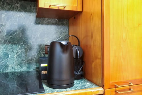 Bollitore elettrico nero su piano in marmo nella zona cucina dello studio Urban Nest dell'hotel Milano