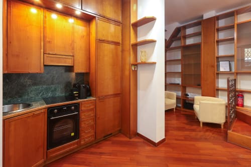 Cucina in legno moderno e zona living nello studio Urban Nest di Solumnia Milano con elettrodomestici integrati e design contemporaneo