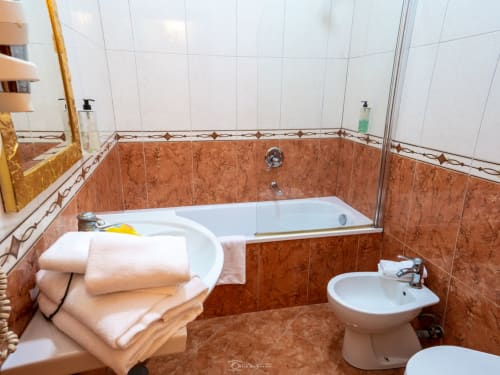 Ampio bagno del B&B Alla Basilica con piastrelle in cotto, vasca bianca, lavabo e bidet a San Giovanni