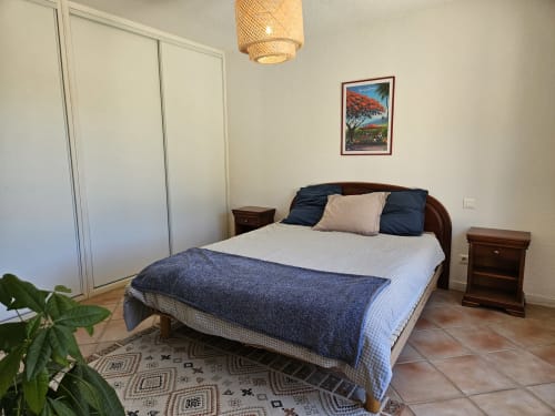 Chambre spacieuse au Domaine de L'Échappée Belle à Entrecasteaux avec lit en bois, literie bleu marine, suspension tissée, et