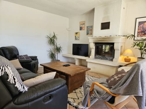 Salon moderne avec cheminée, fauteuil inclinable en cuir noir et plantes en pot à la villa Domaine de L'Échappée Belle