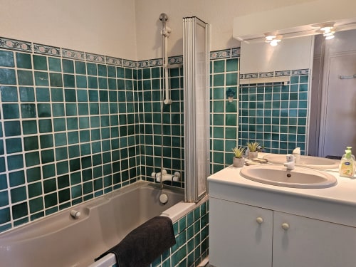 Salle de bain moderne aux murs en carrelage bleu-vert, vasque blanche et baignoire à la Villa Les Cyprès du Domaine de L'Échappée Belle,