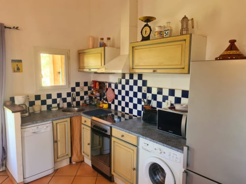 Small kitchen at Domaine de L'Échappée Belle in Entrecasteaux with checkered backsplash, yellow cabinets, and vintage