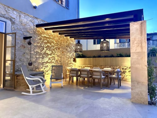 Patio iluminado de Villa Cas Pilot en Son Servera con mesa de comedor, mecedora y arquitectura de piedra al atardecer