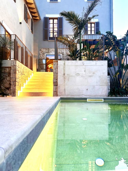 Patio de Villa Cas Pilot con escaleras amarillas iluminadas, piscina poco profunda, palmeras y fachada azul en Son Servera